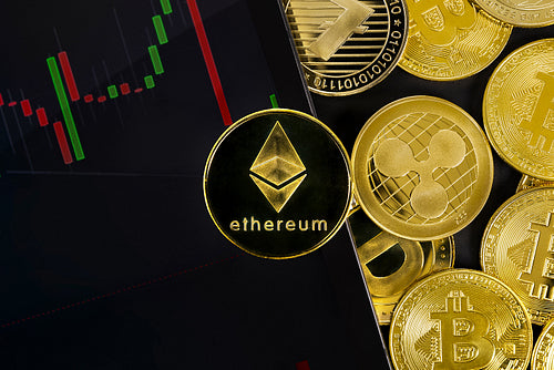Close-up of Ethereum coin on digital tablet with graph by various coins