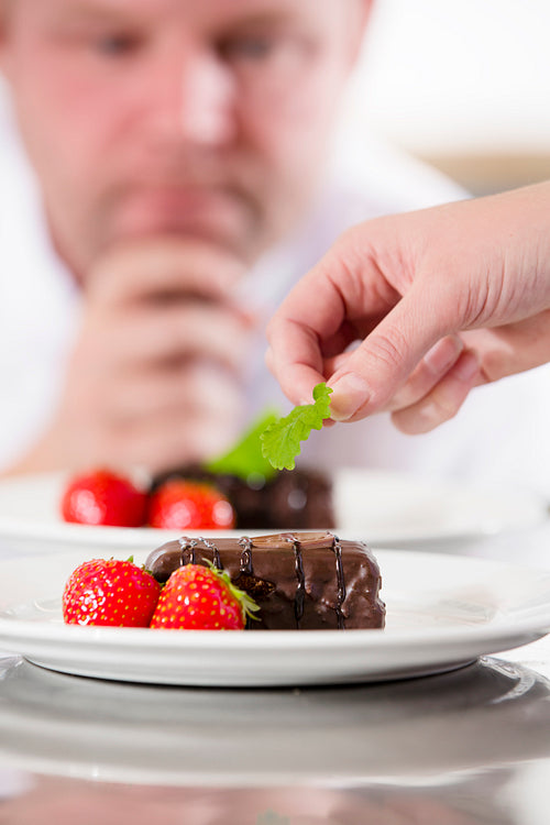 Chef decorate dessert cake with strawberry
