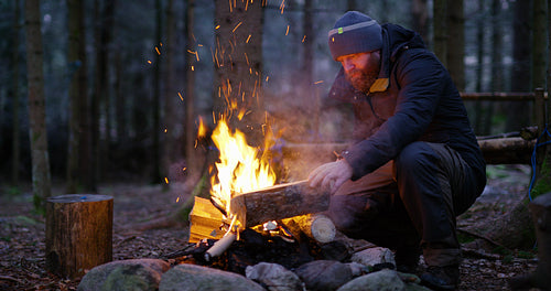 Adult man fires up campfire outdoor in the forest