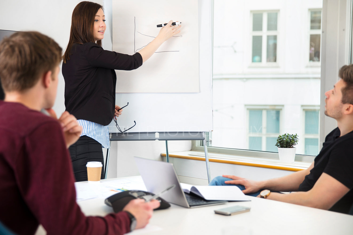 Businesswoman Explaining On Flipchart To Colleagues