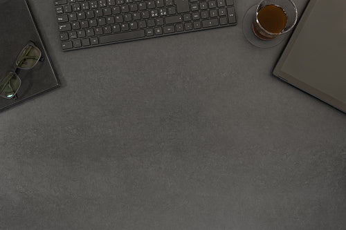 Top view of contemporary black concrete office desk with computer and supplies
