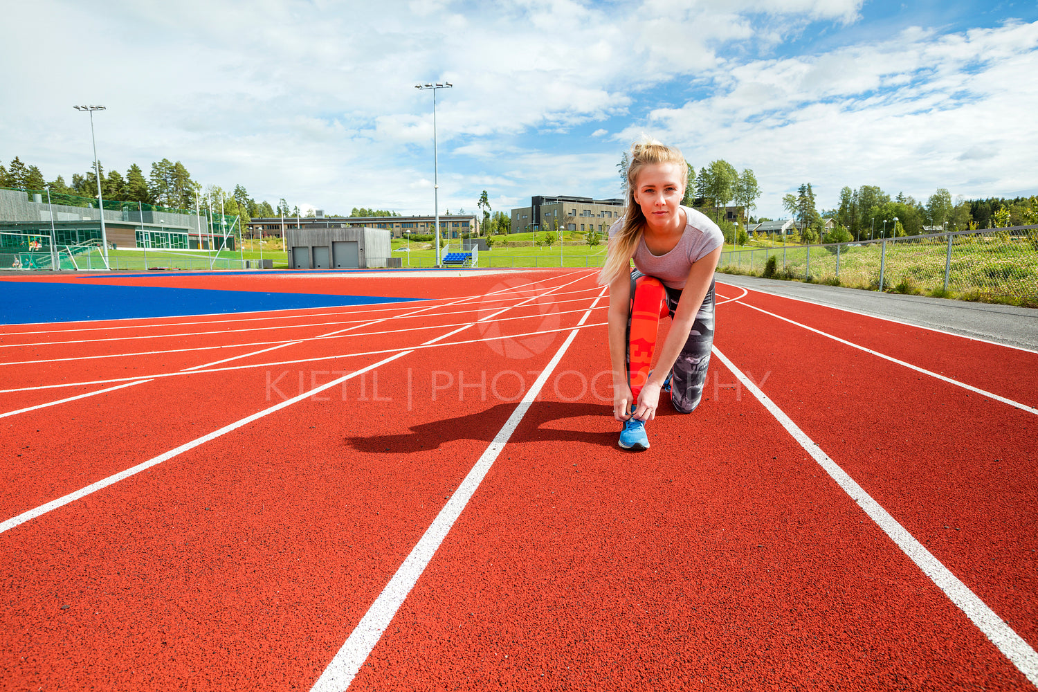 Confident Woman Tying Shoelace On Running Tracks