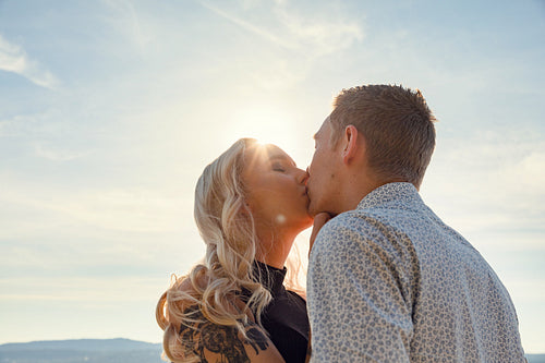 Romantic couple kissing on beach against the sun