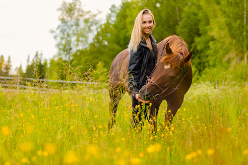 Smiling woman feeding her arabian horse friend with snacks in the field