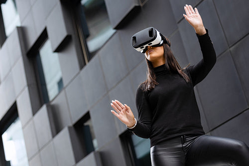 Woman Wearing Virtual Reality Technology Glasses Against Futuristic Building