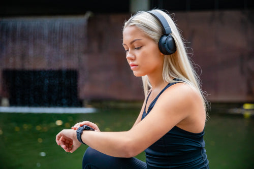Sporty Female Runner Listening Music On Headphones and Using Smartwatch