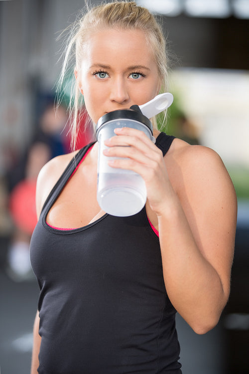Blonde girl drinks water at fitness gym center