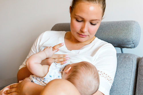 Caring young mother breastfeeds baby girl