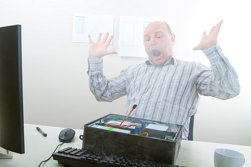 Shocked Businessman Looking At Smoke Emerging From Computer