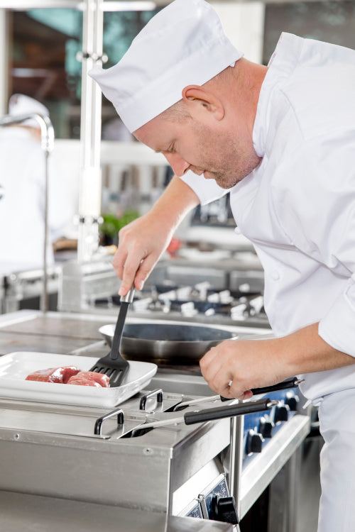 Chef prepares beef steak in pan at the kitchen