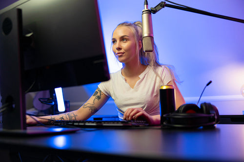 Cool looking professional gamer girl streams and play online multiplayer video game on PC