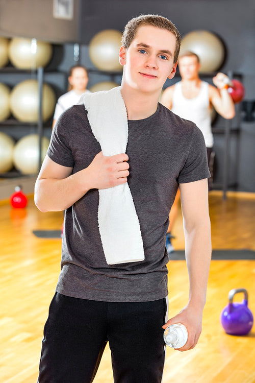 Confident and smiling young man exercising at fitness gym