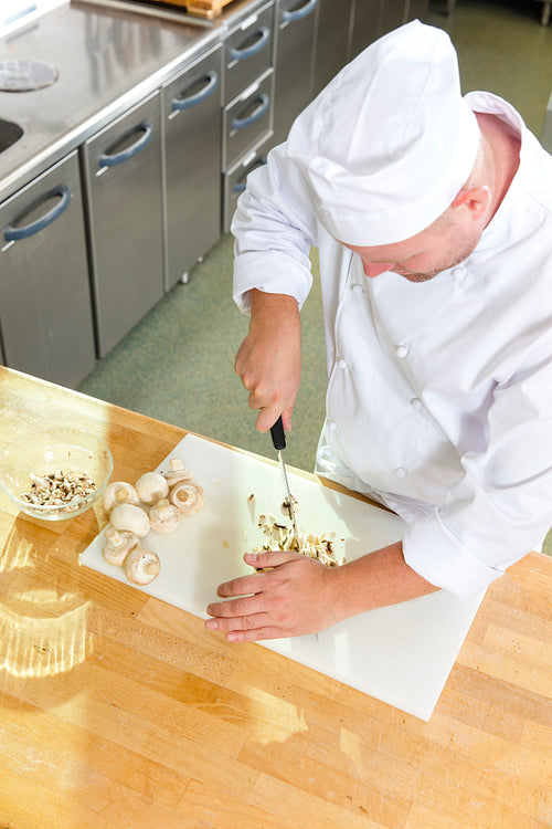 Professional chef preparing mushrooms in large kitchen