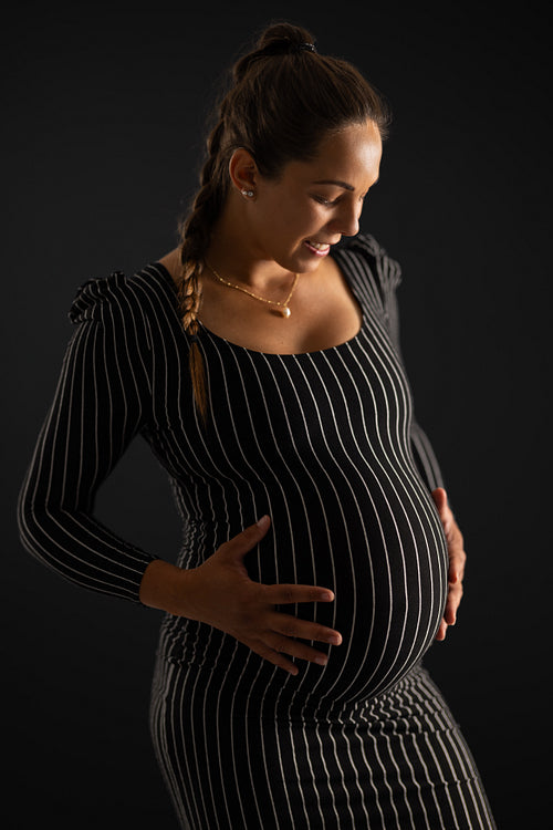 Smiling Pregnant Woman in Striped Dress with Black Background