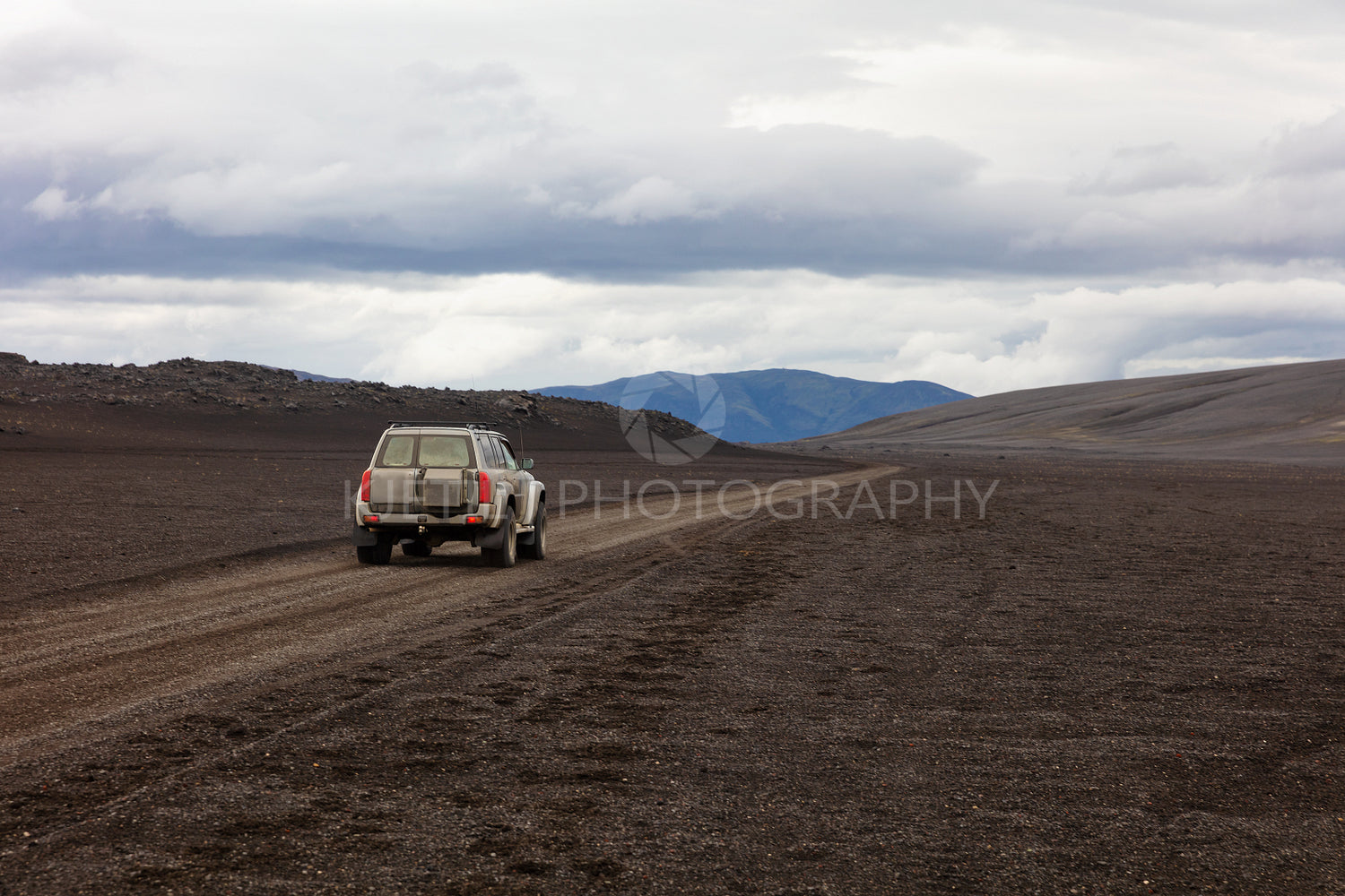 SUV on dirt road against cloudy sky
