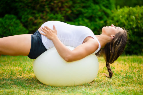 Pregnant Female With Eyes Closed Stretching Back On Yoga Ball