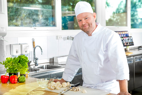 Smiling and confident chef standing in large kitchen