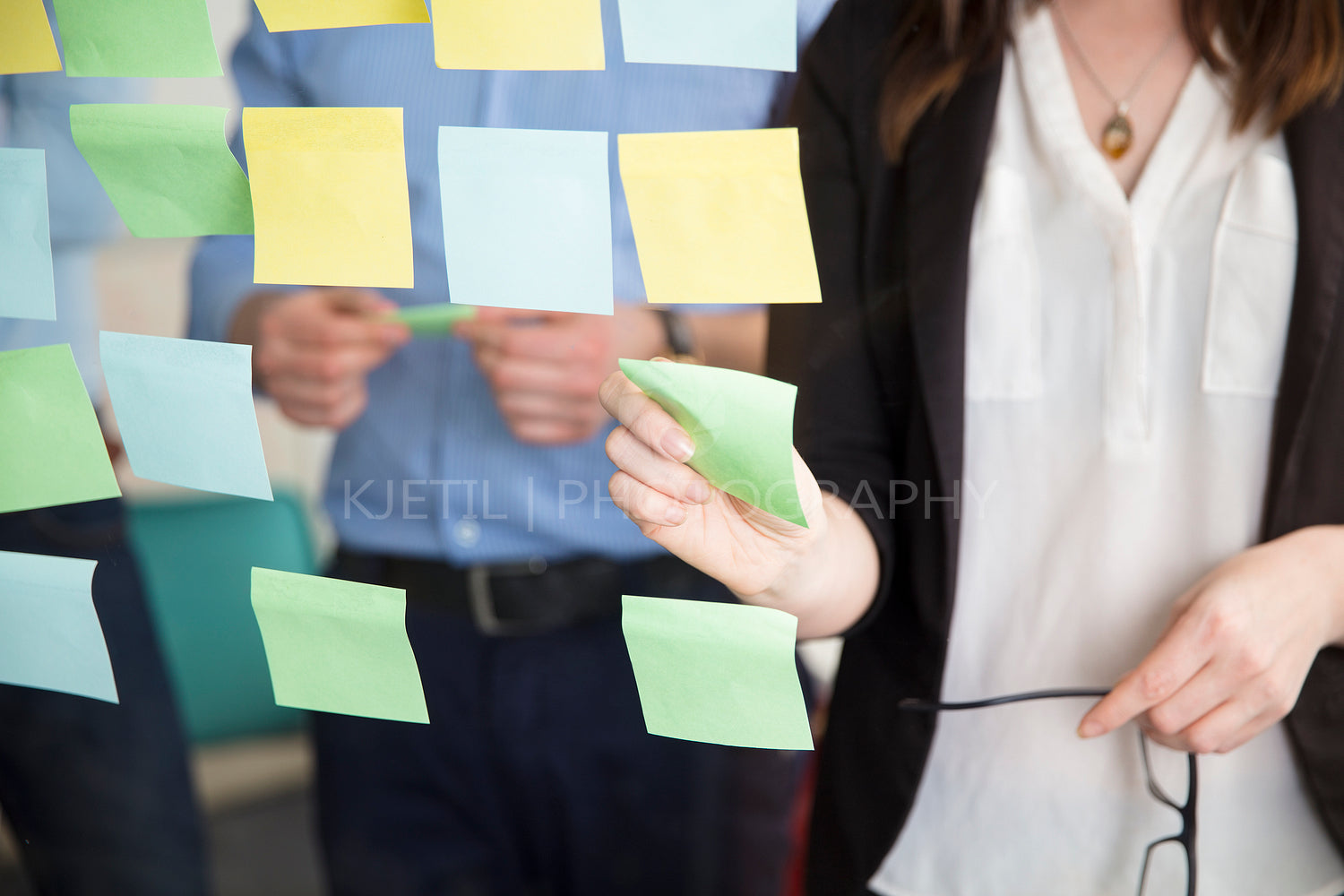 Midsection Of Businesswoman Sticking Note While Standing By Executive