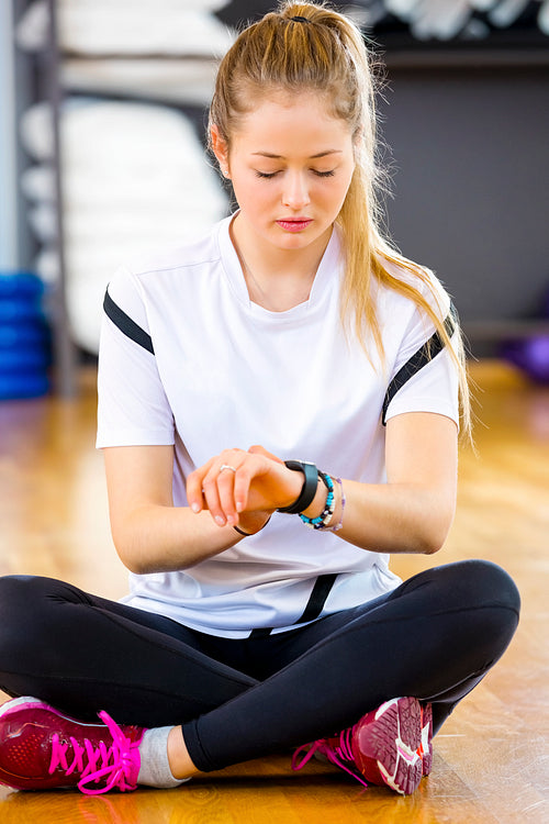 Woman Using Smart Watch While Sitting In Gym
