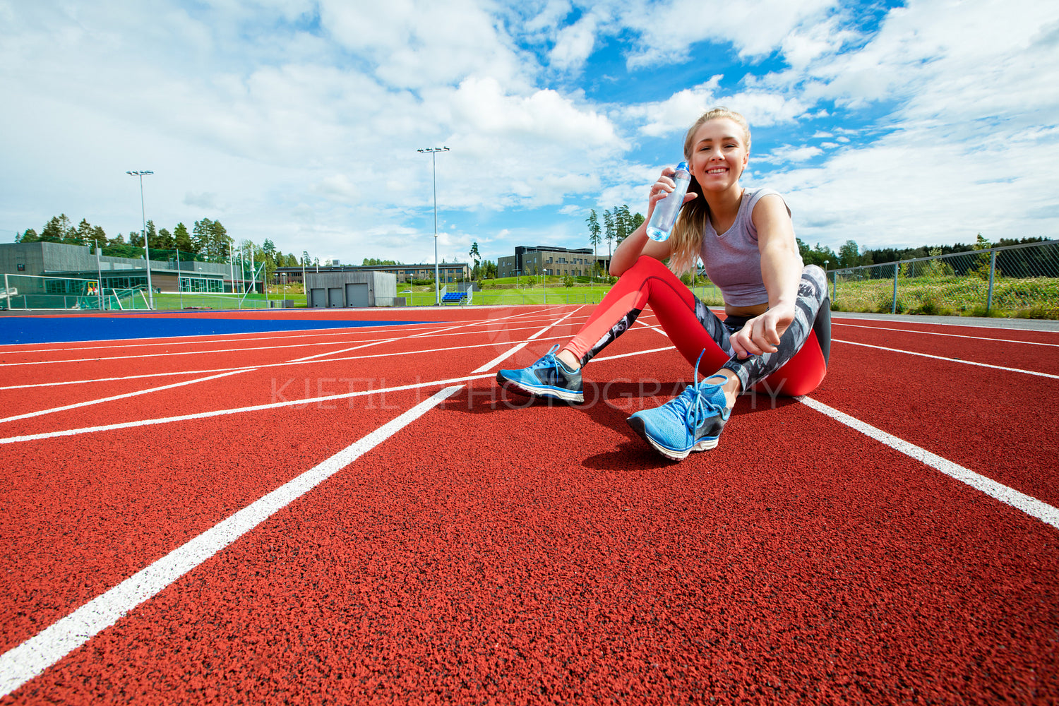 Happy Young Woman Drinking Water On Running Tracks