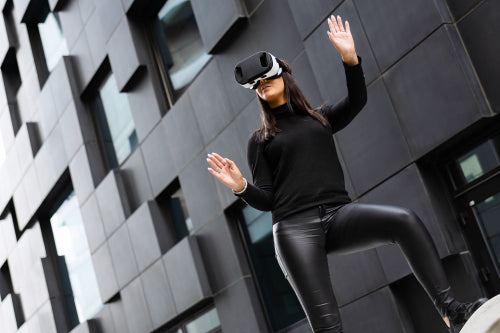 Playing Woman Wearing Virtual Reality Technology Glasses Against Modern Building