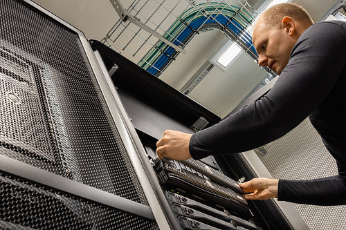 Male IT Technician Installing Server At Datacenter