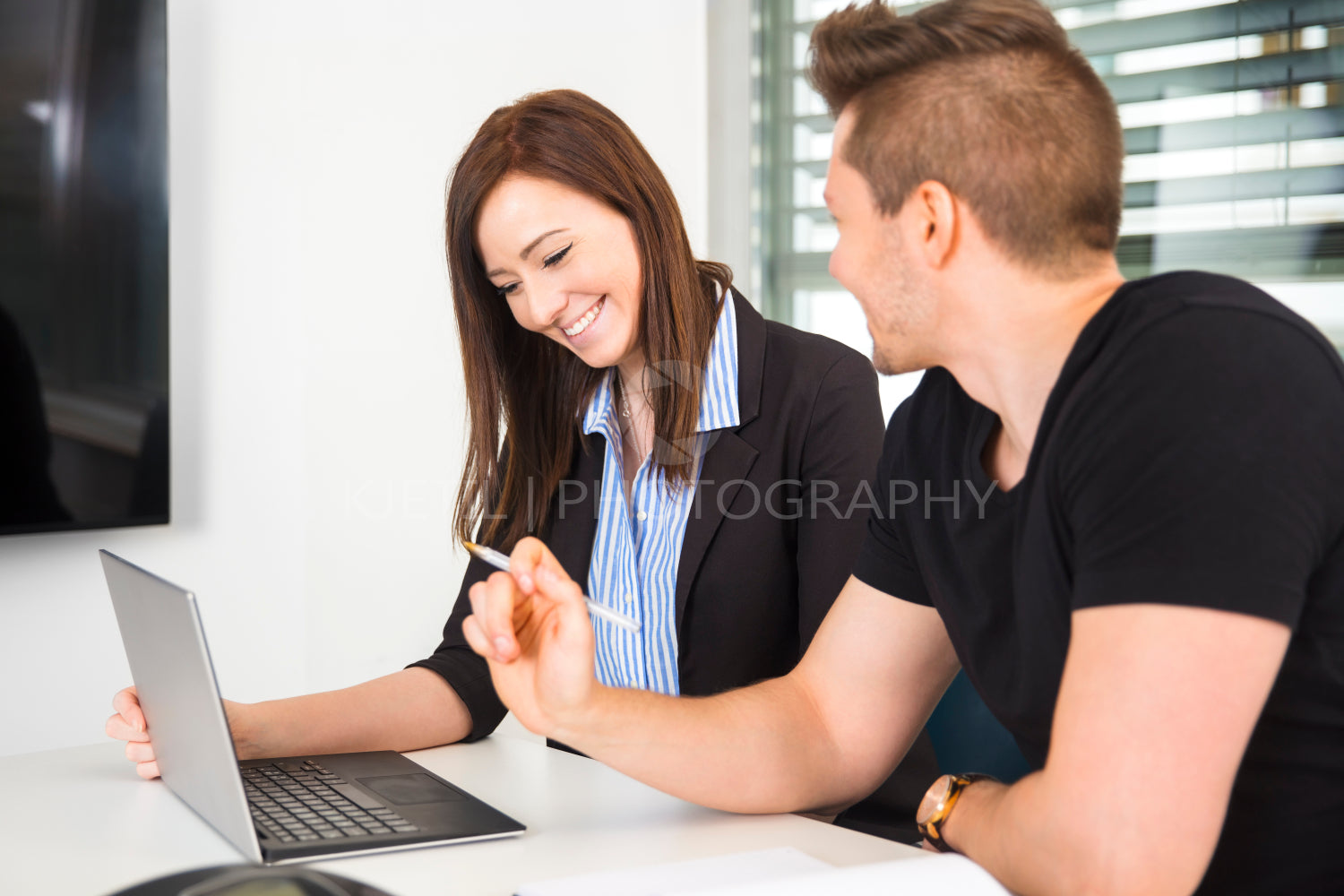 Businesswoman Using Laptop By Colleague At Desk
