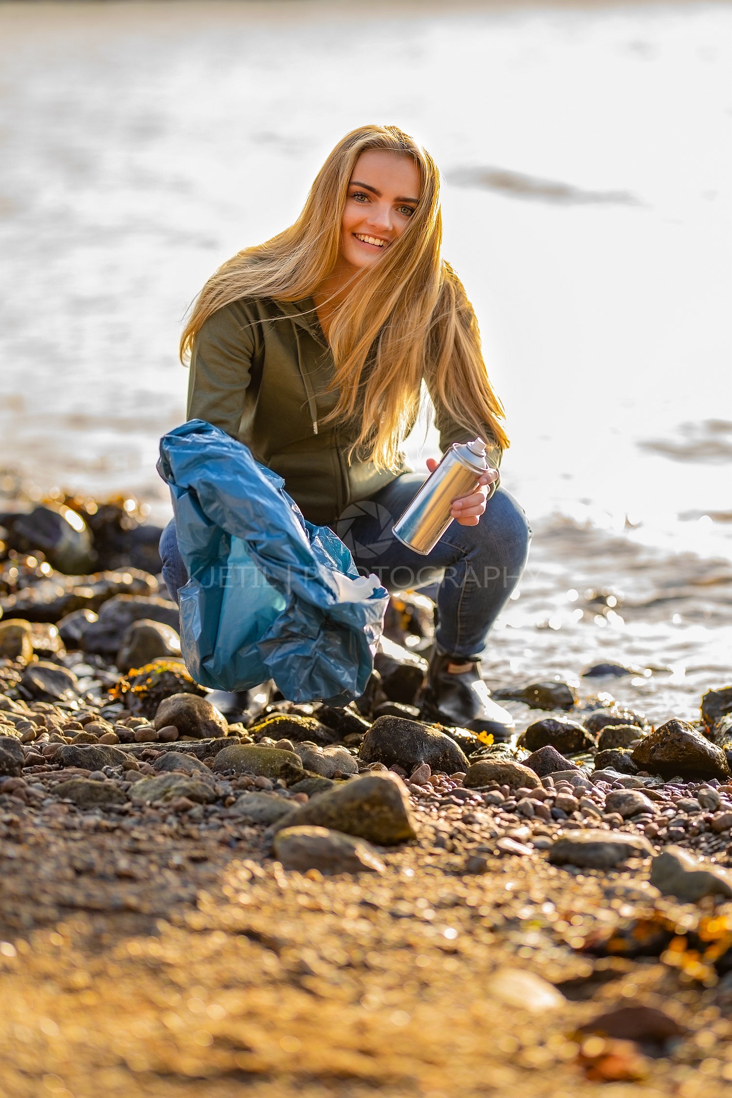 Young woman volunteer picking up aerosol can at beach