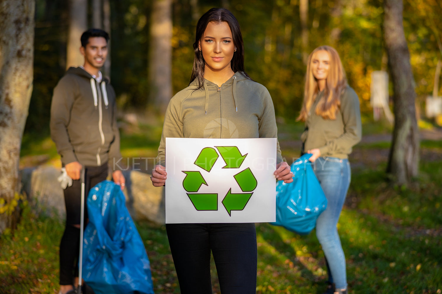 Confident volunteer woman holding recycling symbol placard