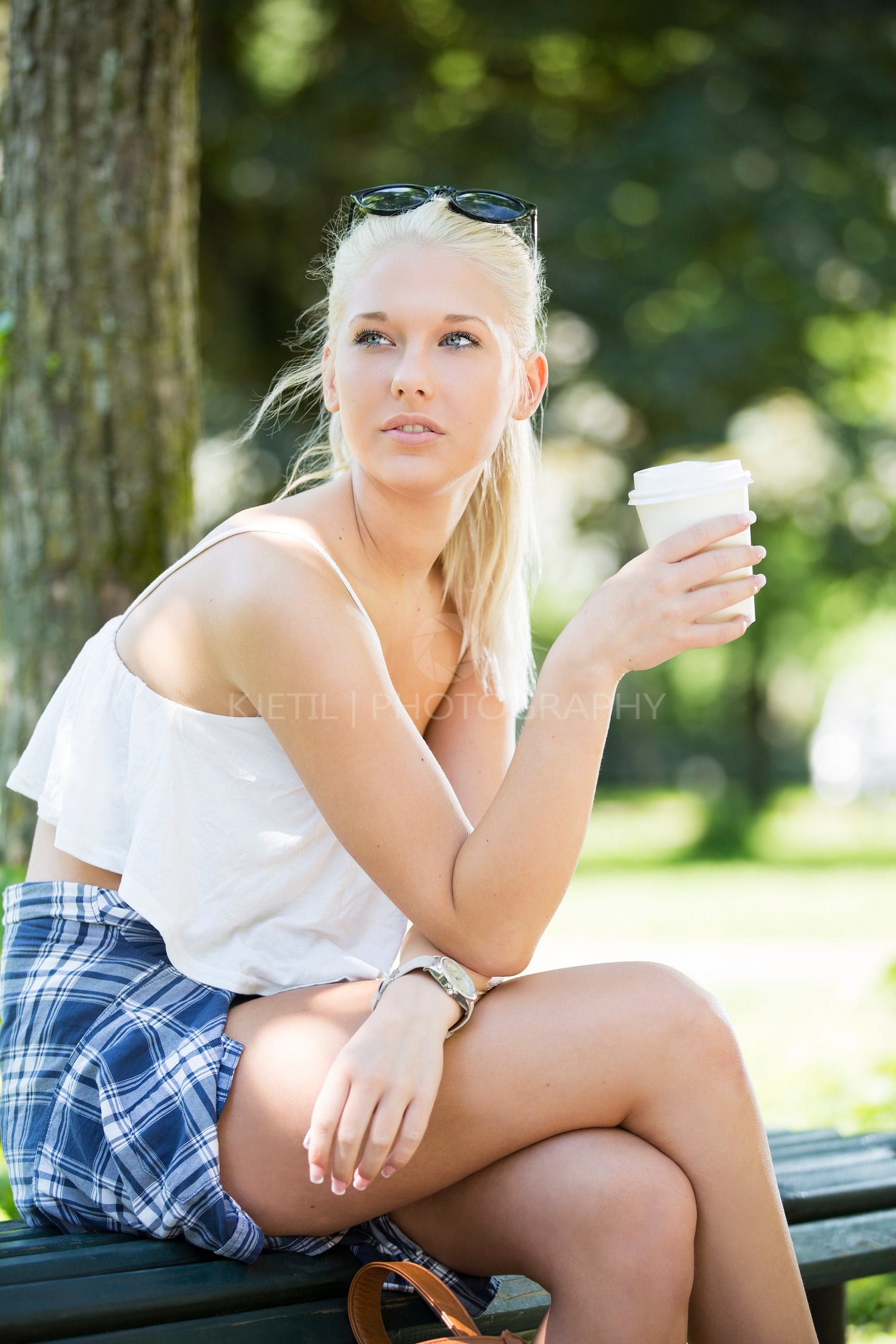 Casual girl sits on a bench and drinks coffee