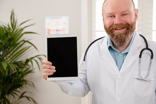 Smiling adult male doctor showing a digital image or report on a tablet