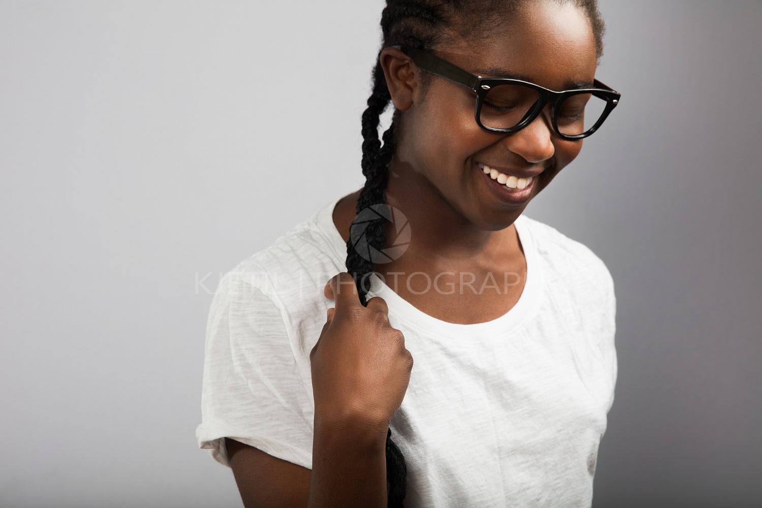 Woman With Braided Hair Wearing Eyeglasses Over Gray Background