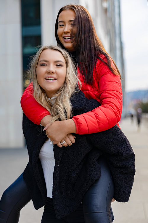 Close-up of Happy Female Friends Having Fun and Piggybacking In City