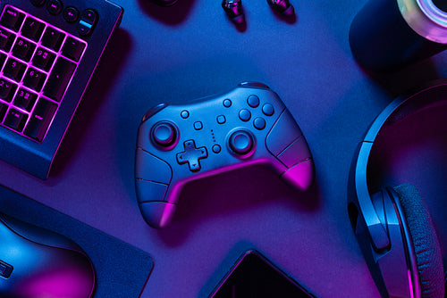 Game controller with purple lit keyboard amidst various wireless devices