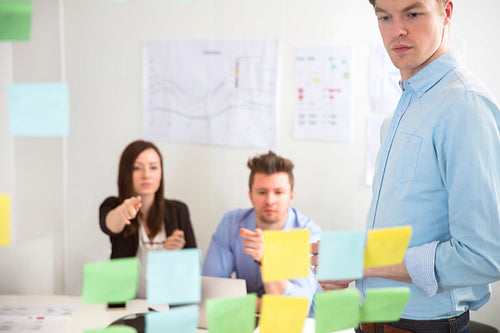 Businessman Looking At Adhesive Notes While Colleagues Pointing