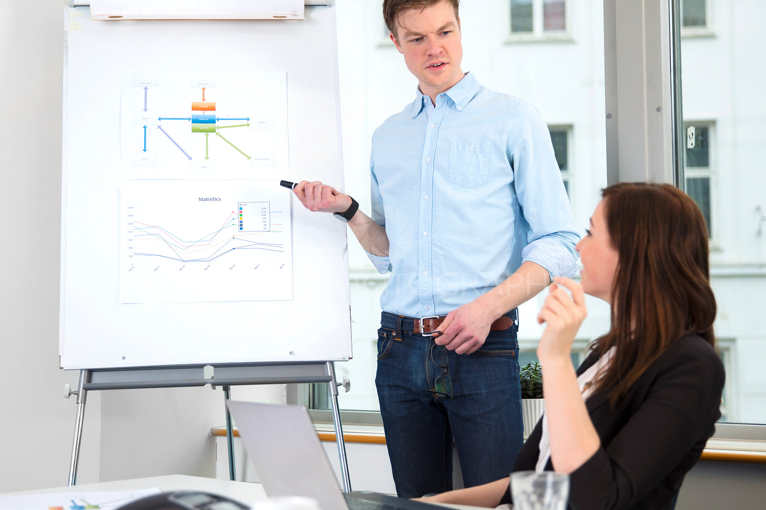 Businessman Giving Presentation To Colleague In Office