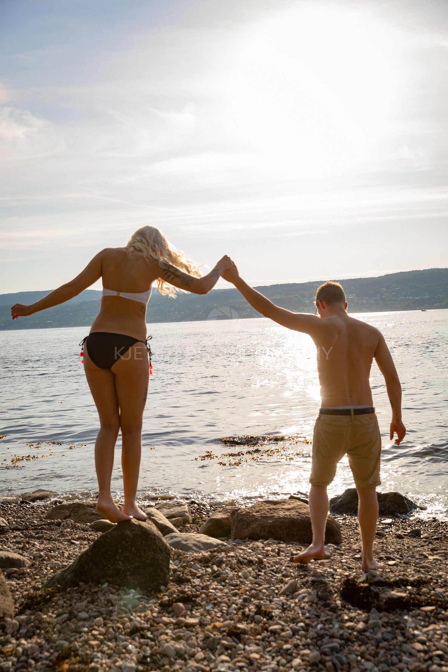 Couple in love holding hands at the beach against sun
