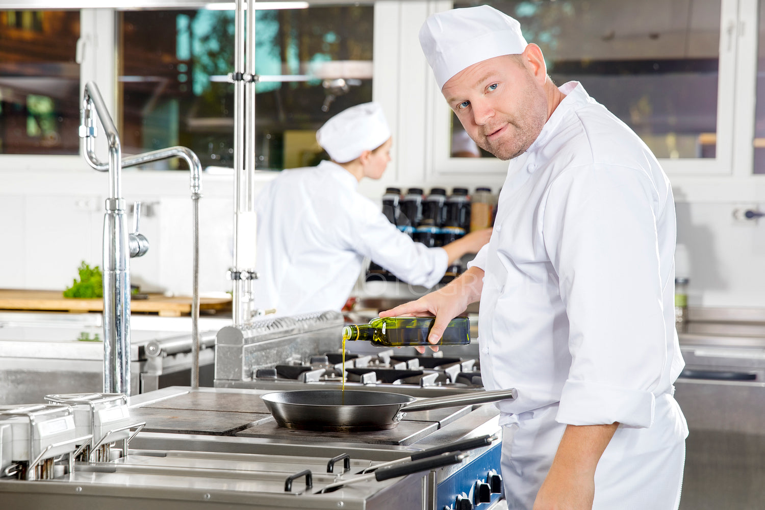 Chef pours olive oil in pan at a professional kitchen