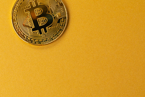 Gold bitcoin cryptocurrency coin on gold yellow backgound