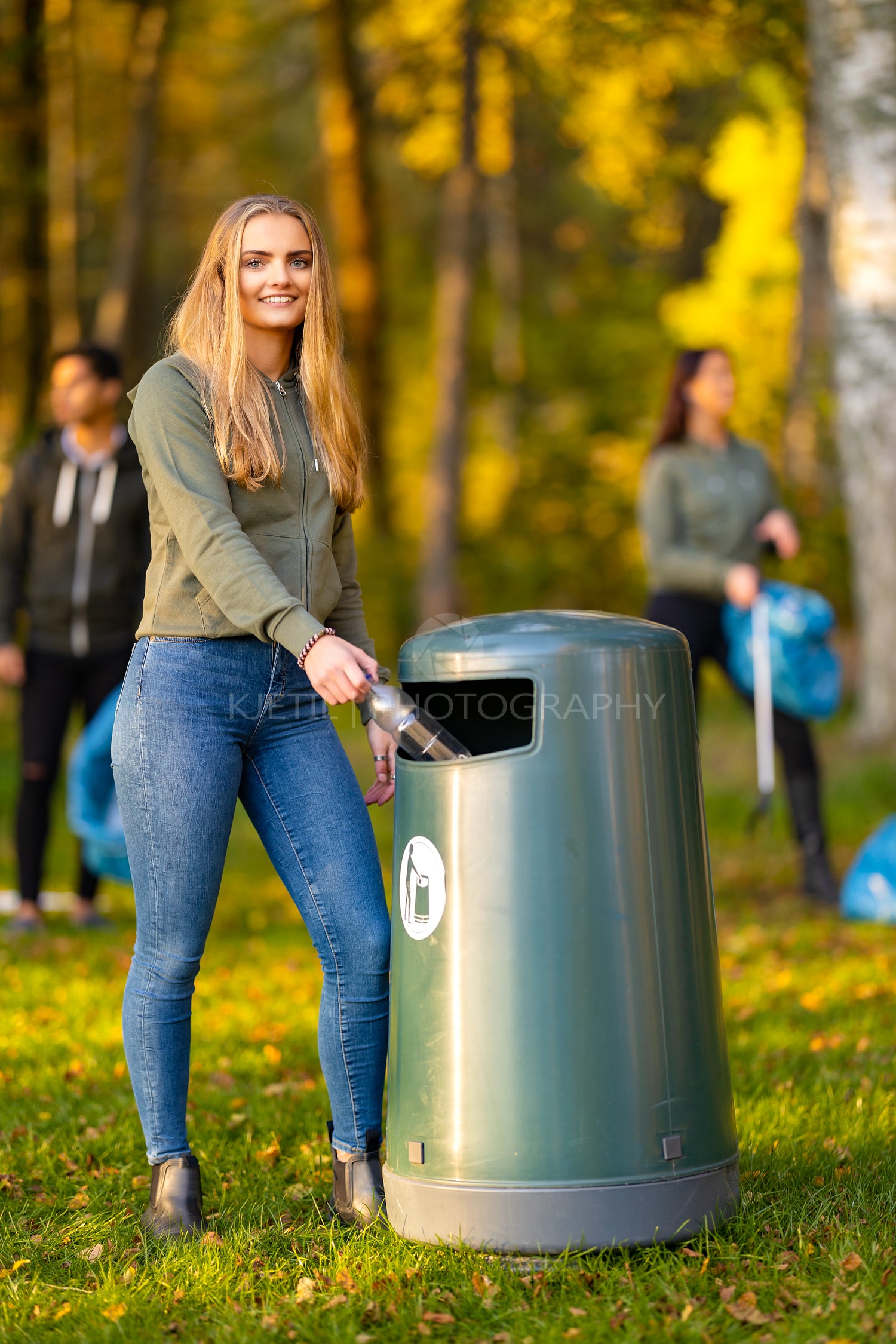 Smiling young woman putting bottle in garbage bin