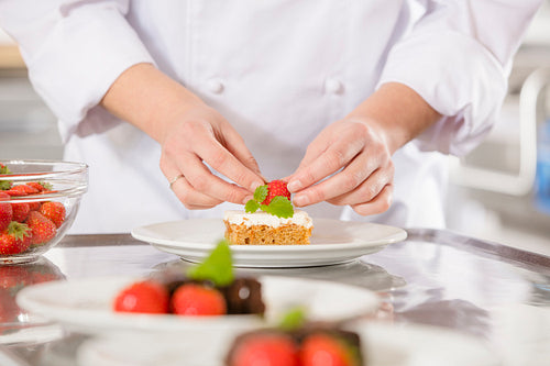 Chef decorates dessert cake with strawberry