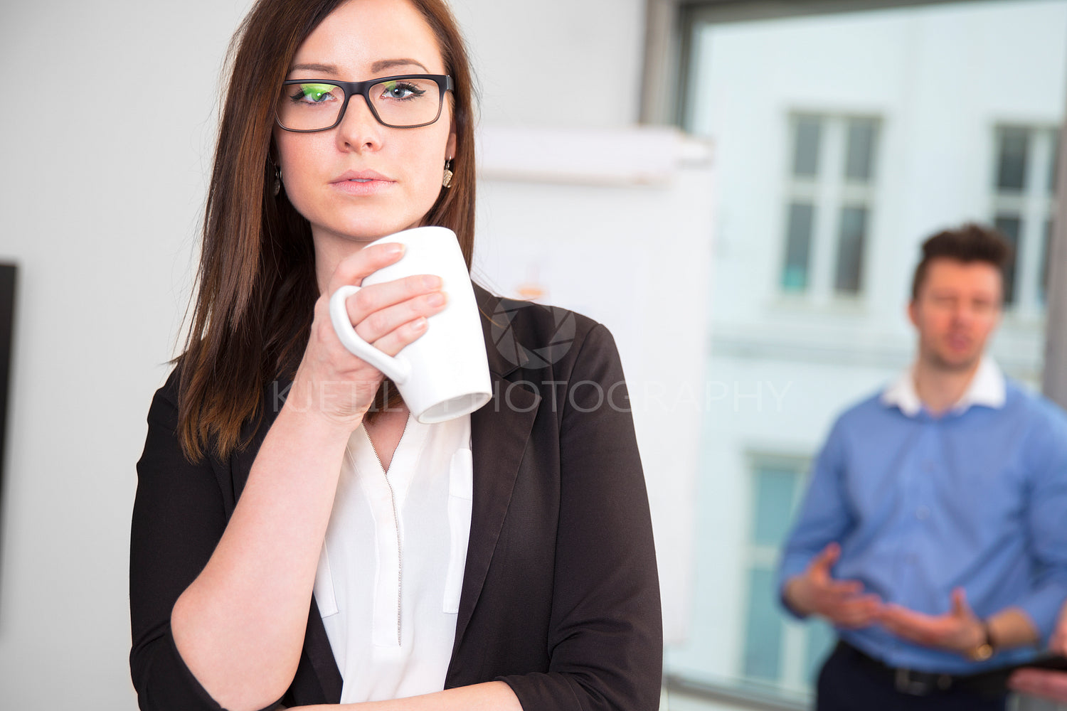 Businesswoman Holding Coffee Mug While Colleague Standing In Bac