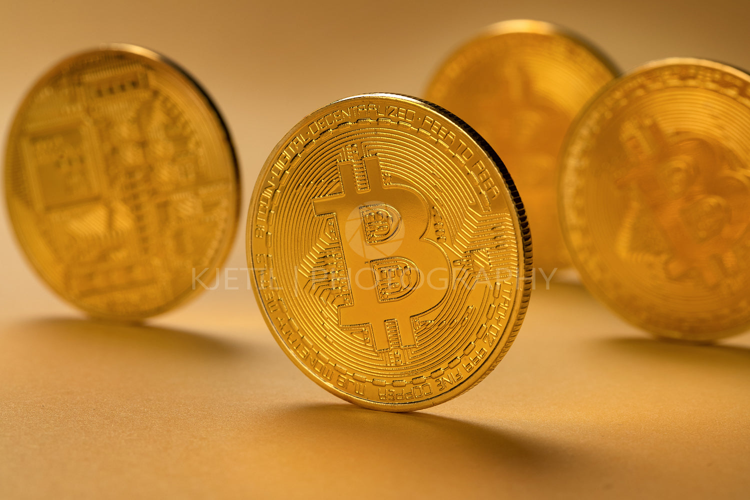 Closeup of gold bitcoin coins standing on yellow backgound
