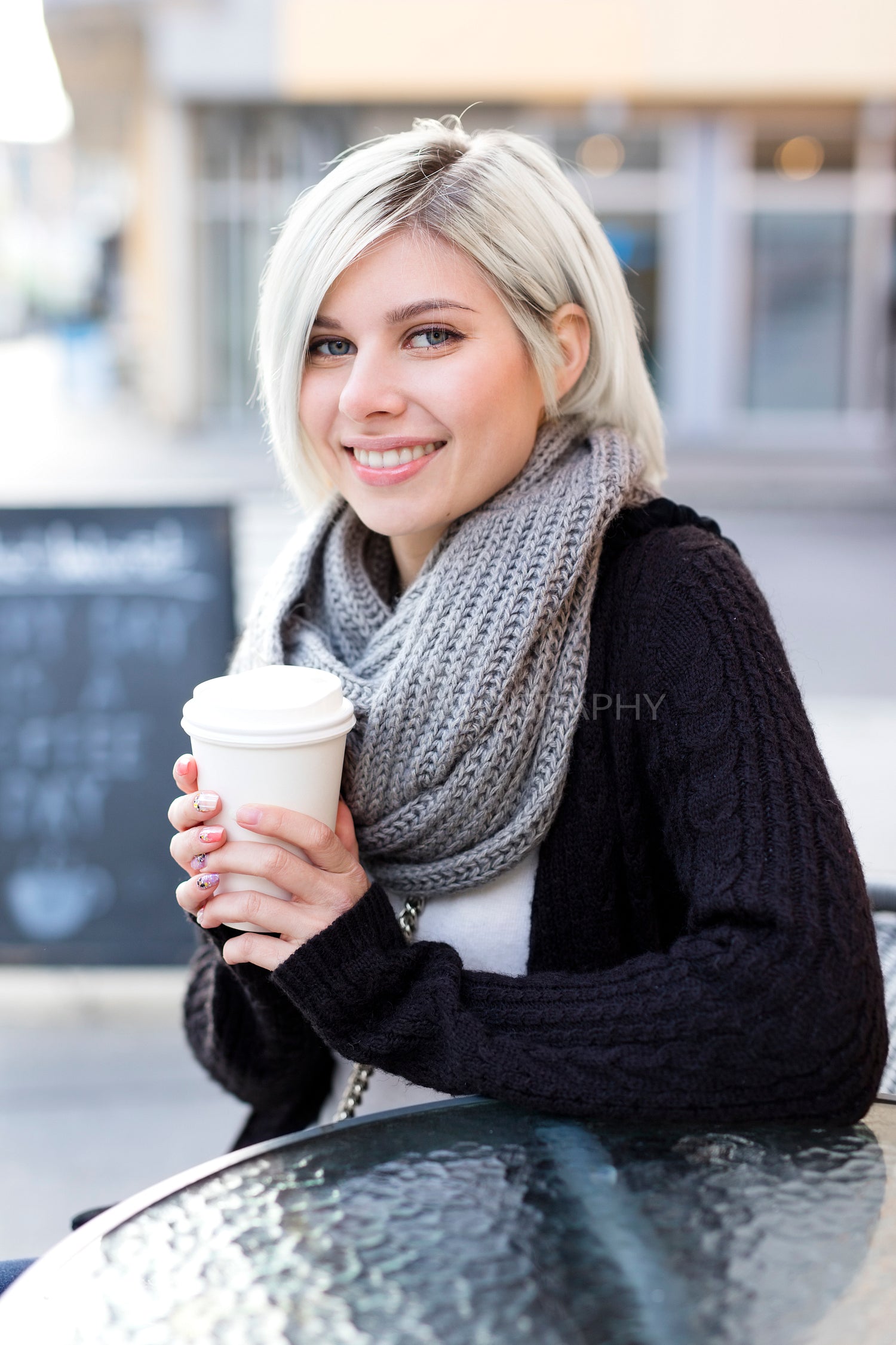 Smiling blonde woman drinking coffee outdoor at cafe