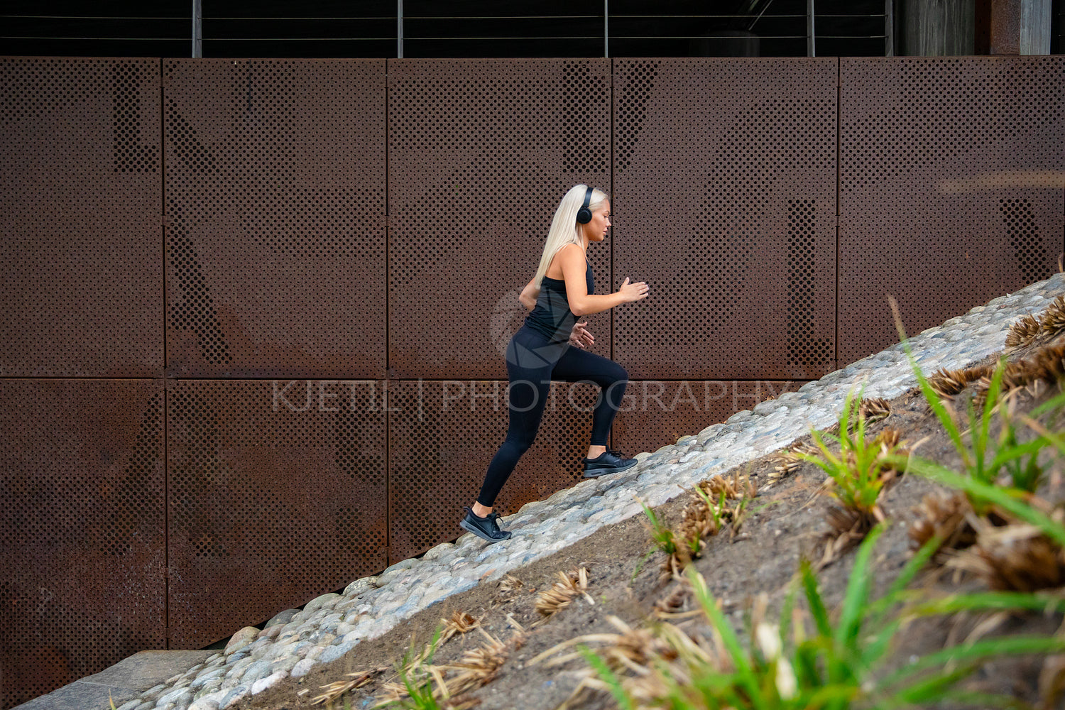Fit attractive sports women running fast in stairs against a metal wall in city