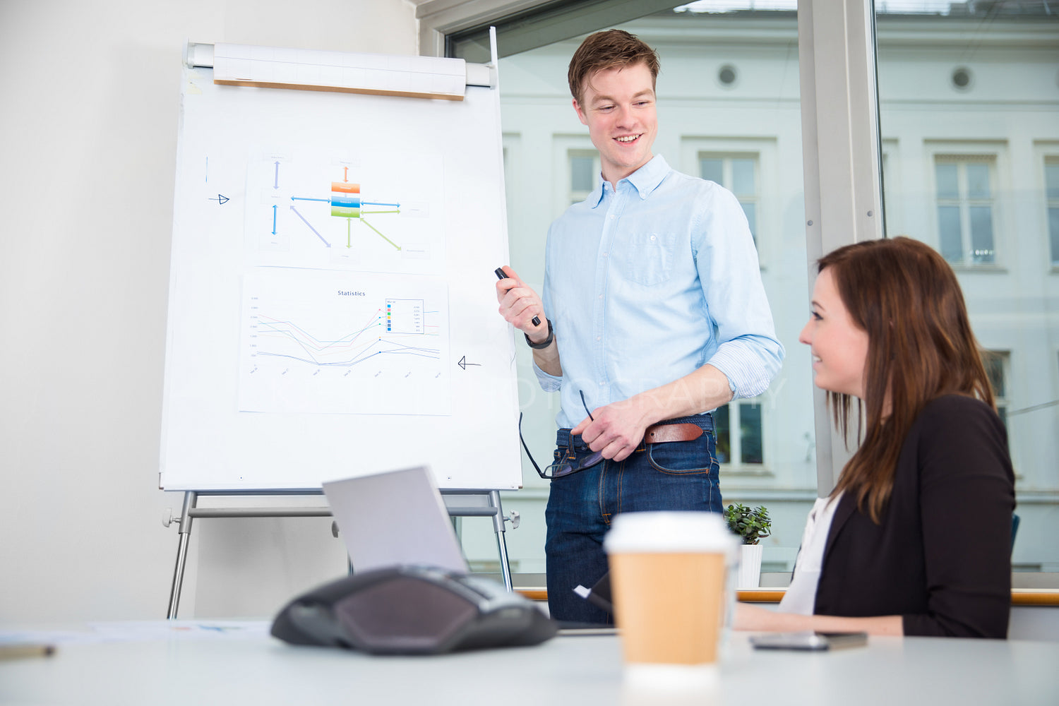 Smiling Businessman Giving Presentation To Colleague In Office