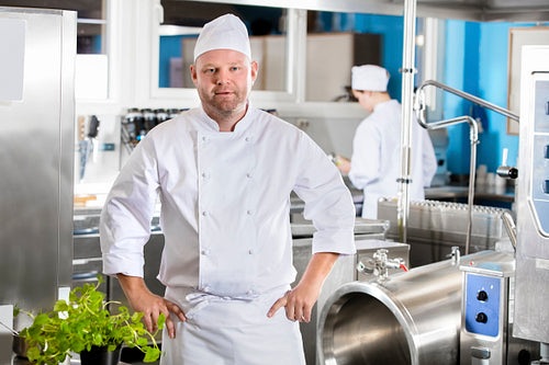 Portrait of confident and smiling chef making food in large kitchen