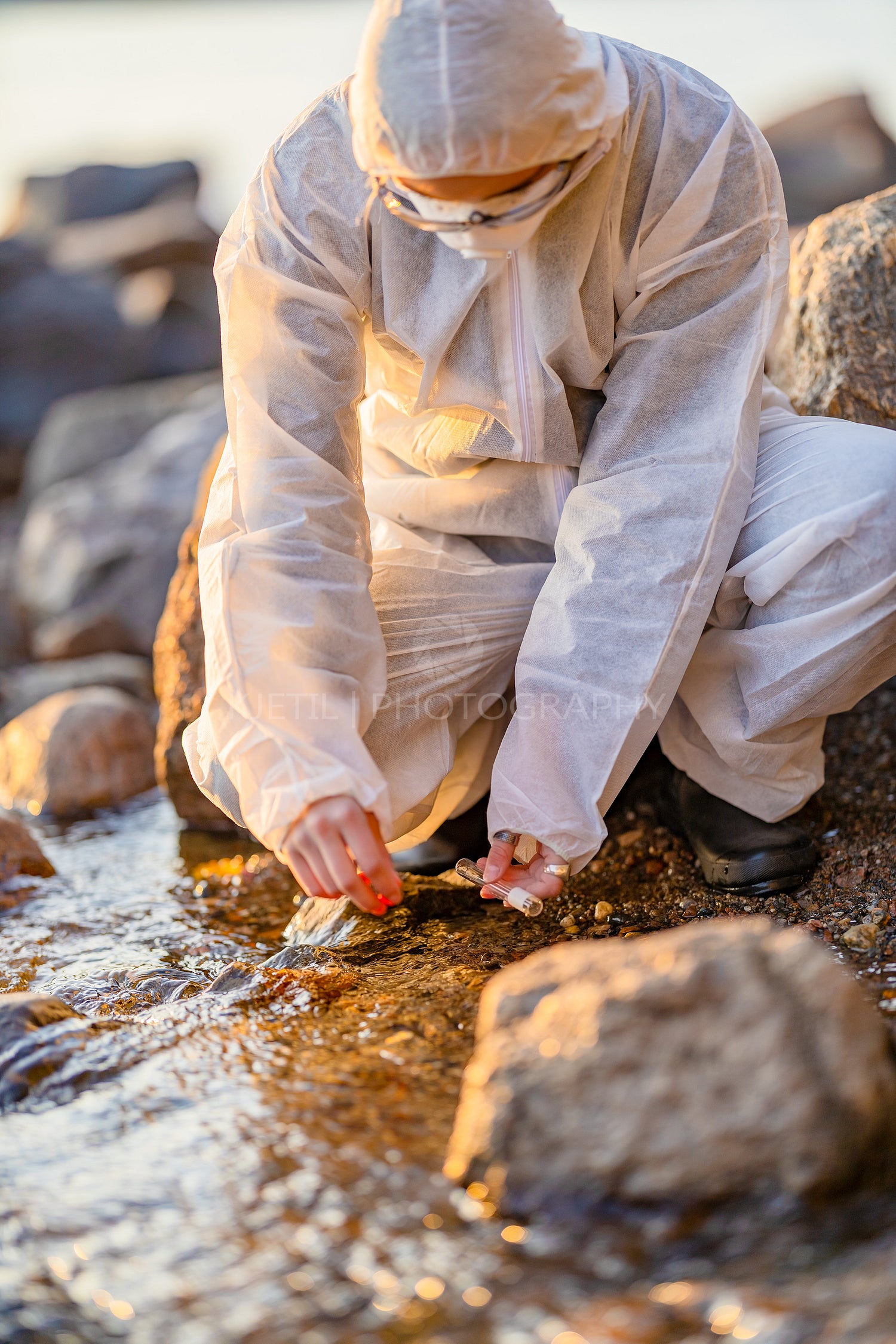 Close-up of researcher collecting water sample at seashore