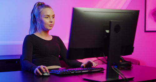 Beautiful E-sport Gamer Girl with Headset Playing Online Video Game on PC