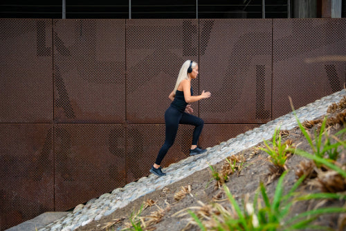 Fit attractive sports women running fast in stairs against a metal wall in city